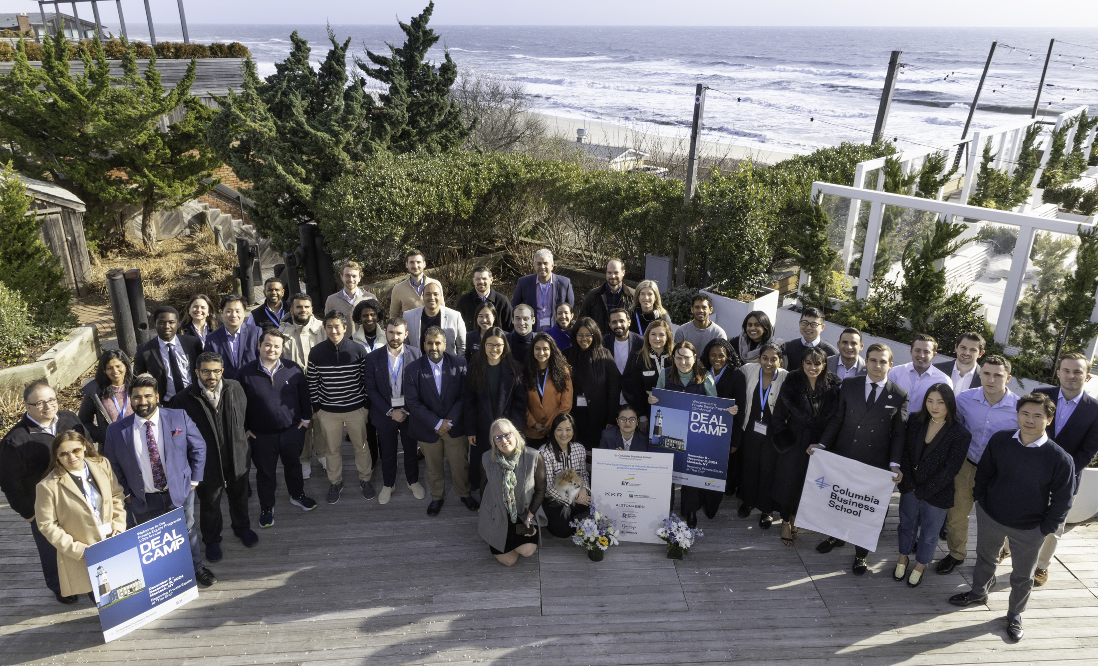 Group photo of Columbia Business School students and participants at Deal Camp with a scenic ocean backdrop.