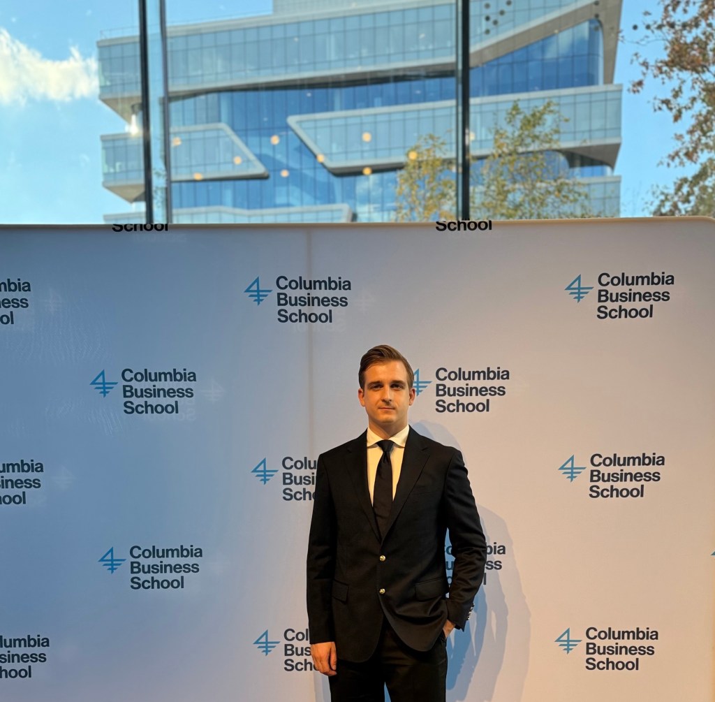 Tomasz Felpel at Columbia Business School event, standing in front of the CBS branding wall.